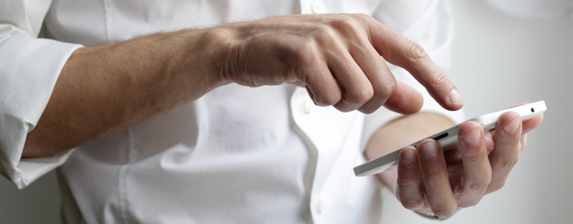 Männerhand tippt auf Smartphone. Kontakt Alexander Herweg.